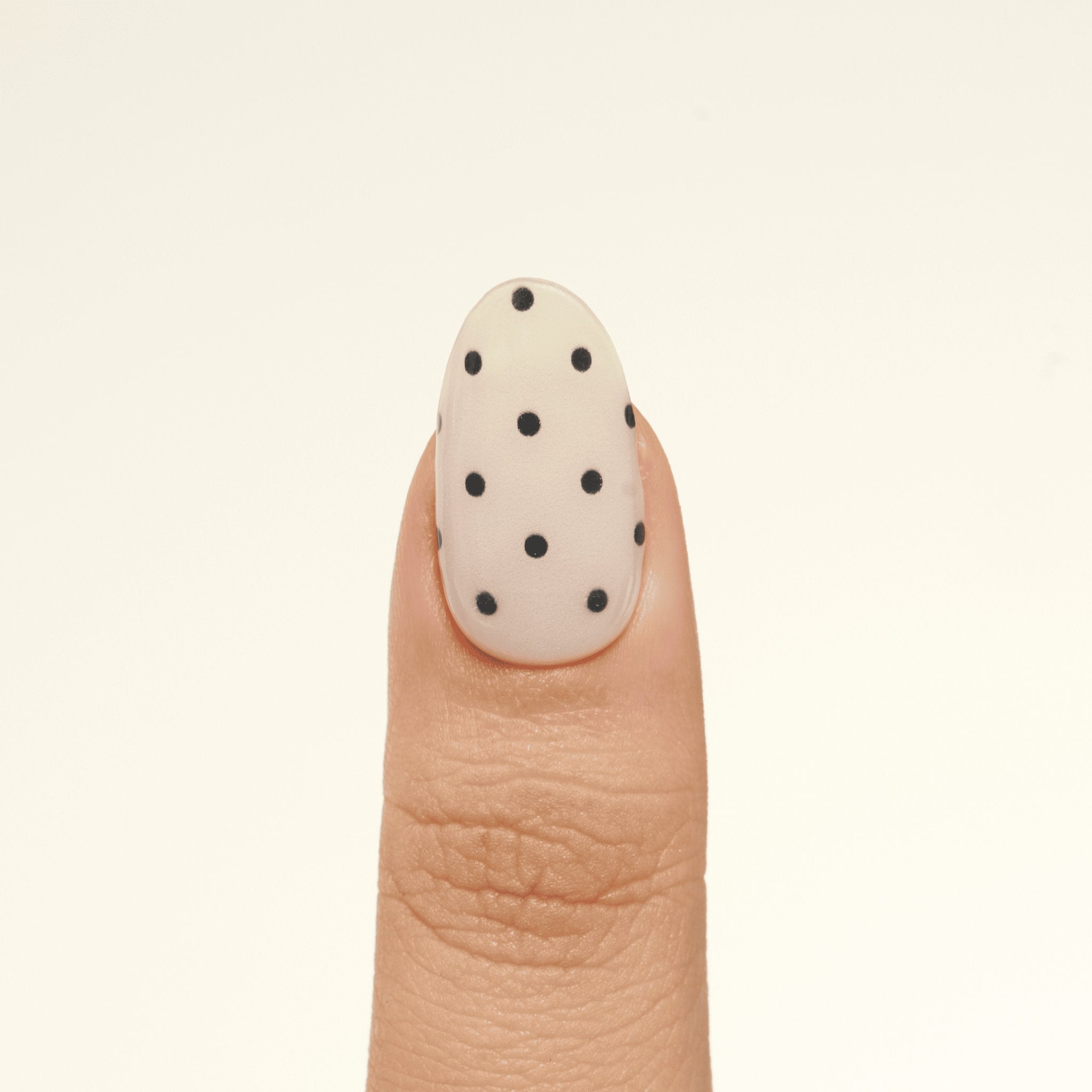Close-up of one Milky White & Black Polka Dot GEWEL™ nail – black dots on a milky white sheer base