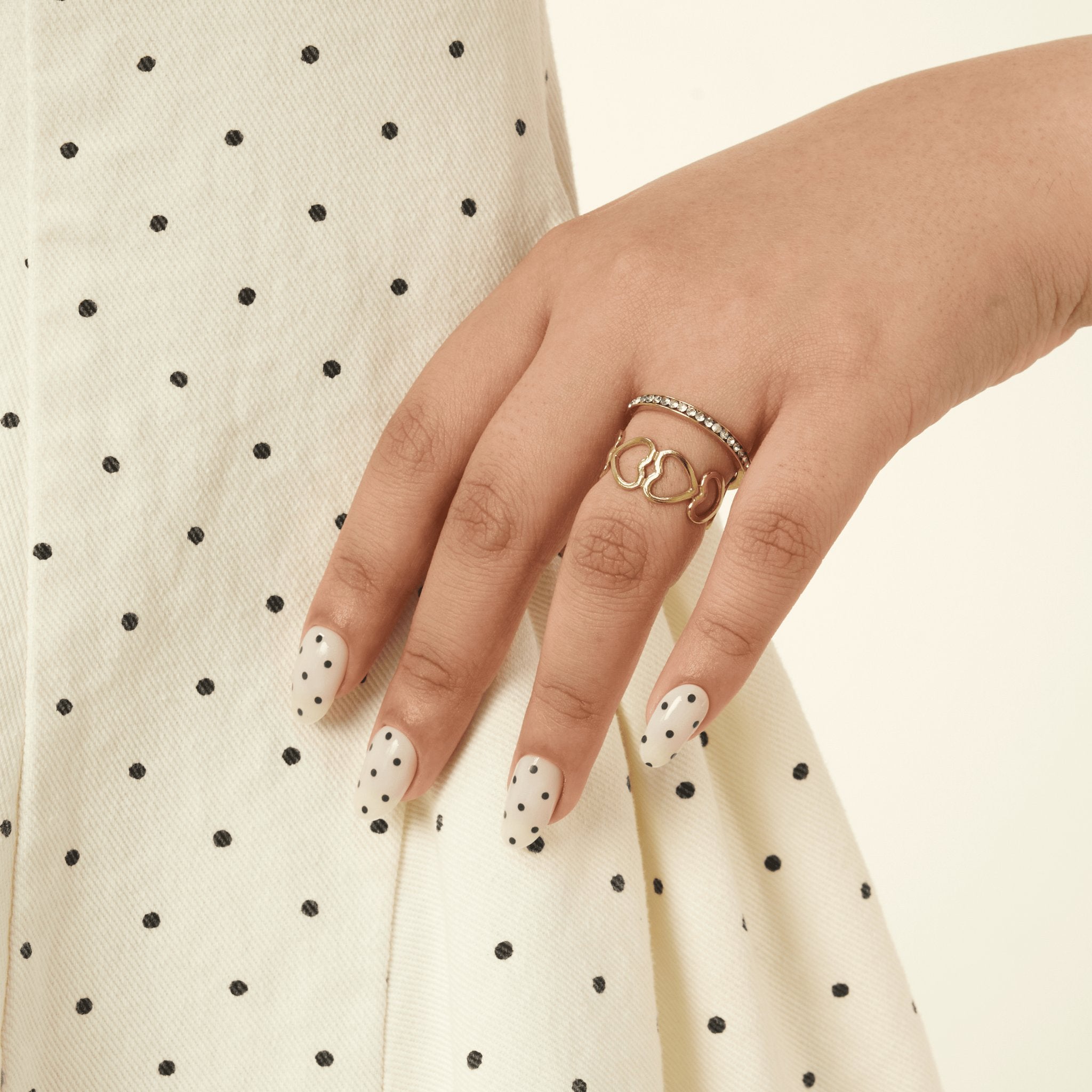 Milky White & Black Polka Dot GEWEL™ nails styled with a cream polka dot skirt
